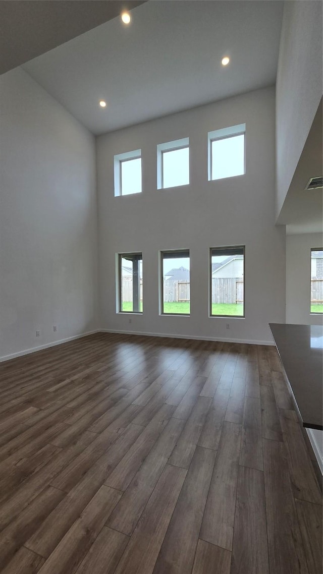 unfurnished living room featuring dark hardwood / wood-style flooring, a high ceiling, and a wealth of natural light