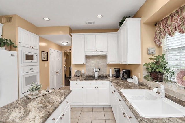 kitchen featuring custom exhaust hood, white cabinetry, white appliances, light tile patterned floors, and sink