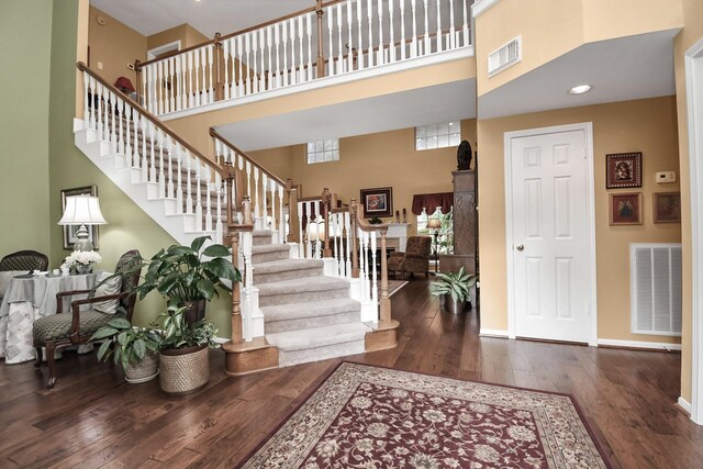 entrance foyer with dark hardwood / wood-style floors and a towering ceiling