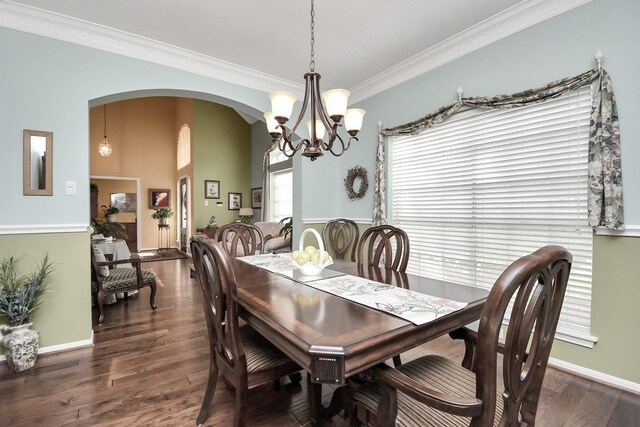 dining space with dark wood-type flooring, ornamental molding, and a chandelier