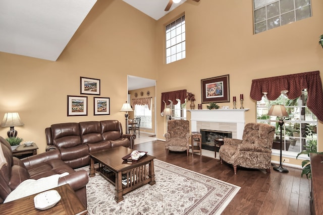 living room with high vaulted ceiling, a fireplace, dark hardwood / wood-style flooring, and ceiling fan