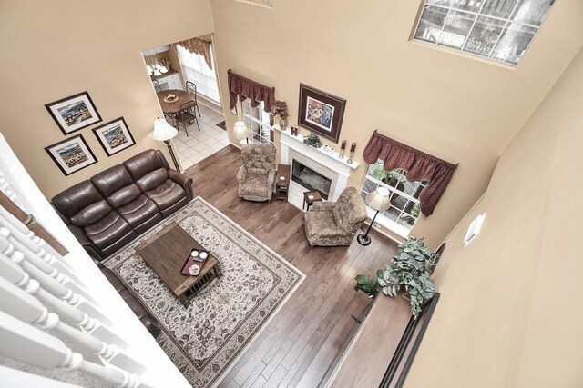 living room featuring dark wood-type flooring, a high end fireplace, and a towering ceiling