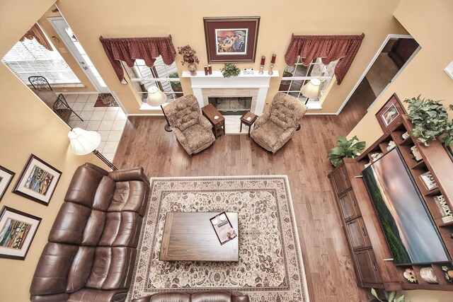 living room featuring a towering ceiling, hardwood / wood-style floors, and a tile fireplace