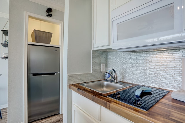 kitchen featuring stainless steel fridge, ornamental molding, sink, wooden counters, and white cabinets