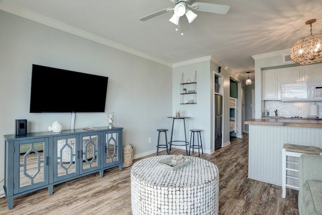 living room with crown molding, ceiling fan with notable chandelier, and hardwood / wood-style floors