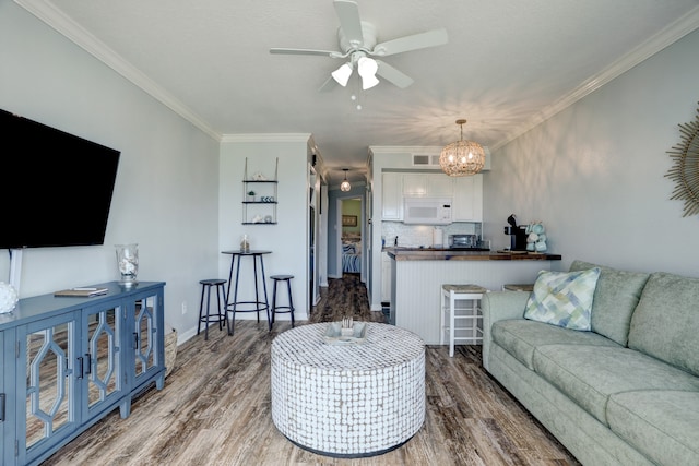 living room featuring ceiling fan with notable chandelier, crown molding, and dark hardwood / wood-style floors