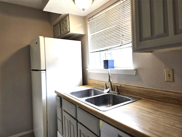 kitchen with white refrigerator, butcher block counters, and sink