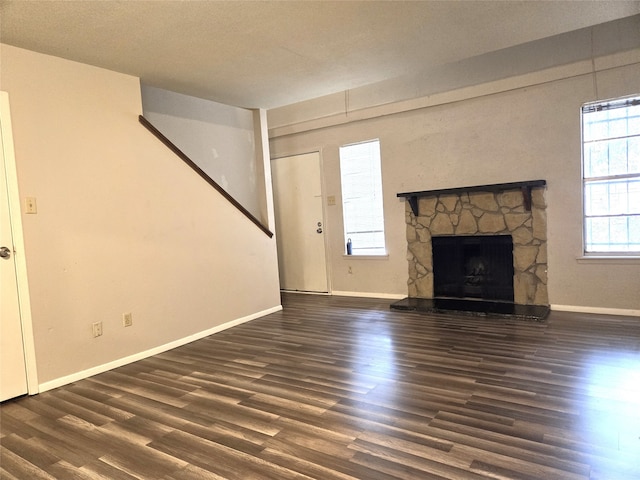 unfurnished living room featuring dark wood-type flooring, a fireplace, and a textured ceiling