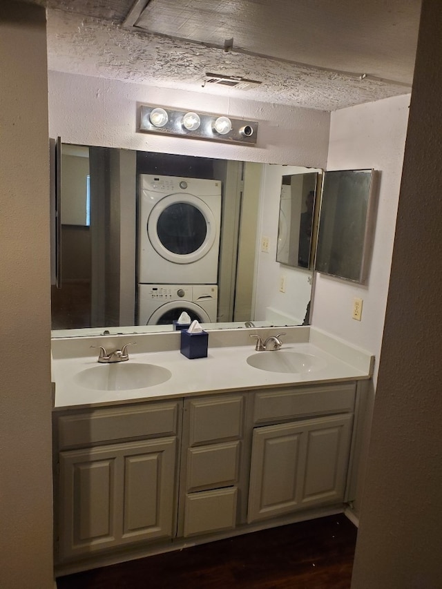 bathroom featuring vanity, a textured ceiling, wood-type flooring, and stacked washer / dryer