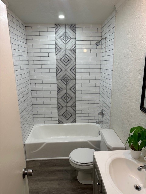 full bathroom featuring wood-type flooring, toilet, tiled shower / bath, and vanity