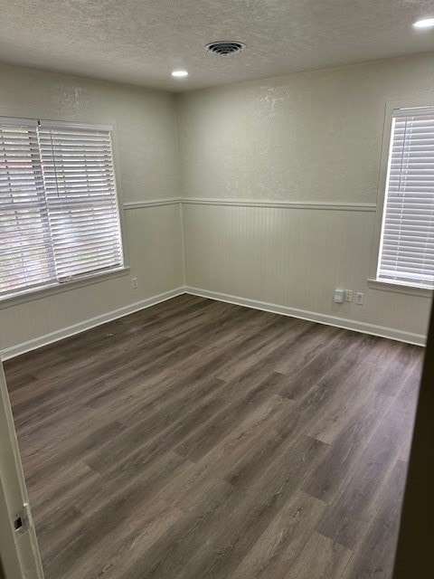 spare room featuring dark wood-type flooring and a textured ceiling