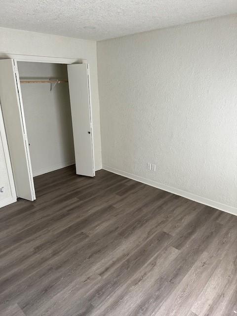 unfurnished bedroom with a closet, dark hardwood / wood-style floors, and a textured ceiling