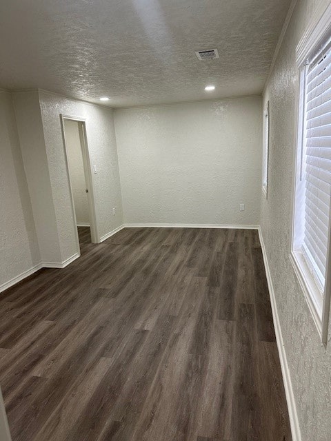 empty room featuring a textured ceiling and dark hardwood / wood-style floors