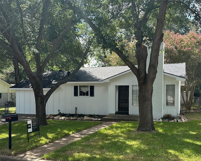 view of front facade featuring a front yard and a shingled roof