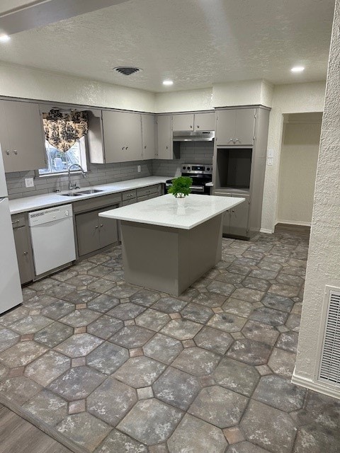 kitchen with white appliances, sink, gray cabinets, a kitchen island, and a textured ceiling