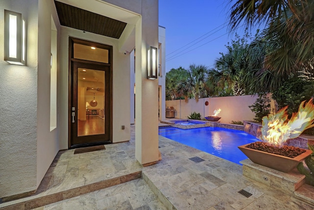 pool at dusk featuring a fenced backyard, a fire pit, an in ground hot tub, a fenced in pool, and a patio area