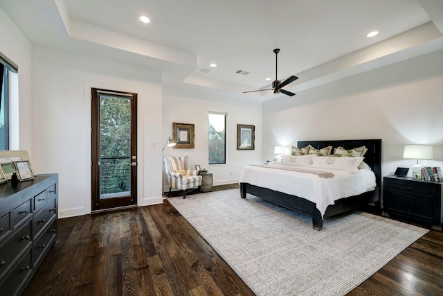 bedroom featuring a tray ceiling, ceiling fan, dark hardwood / wood-style flooring, and access to outside