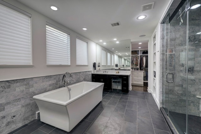 bathroom featuring tile patterned floors, tile walls, independent shower and bath, and vanity