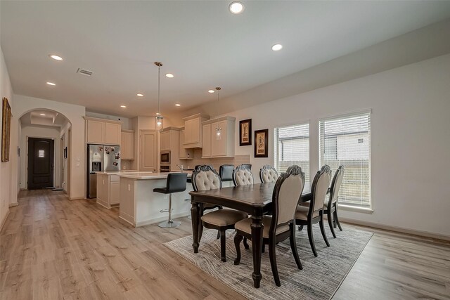 dining space featuring light wood-type flooring, arched walkways, visible vents, and recessed lighting