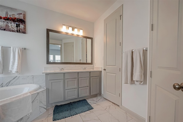 full bath featuring double vanity, marble finish floor, a garden tub, and a sink