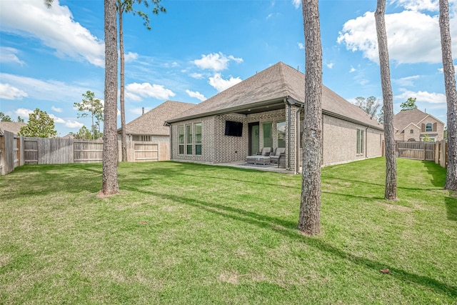 rear view of house featuring a patio, brick siding, a lawn, and a fenced backyard