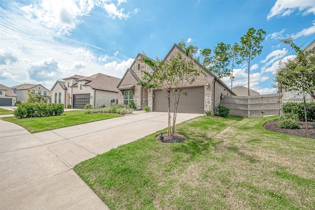 french country style house featuring brick siding, concrete driveway, an attached garage, a front yard, and fence