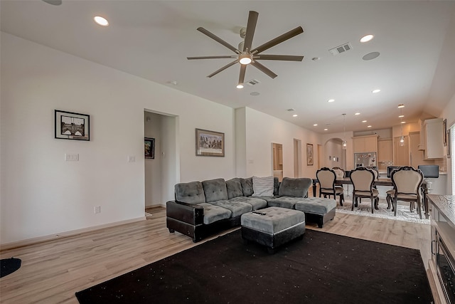 living area featuring recessed lighting, visible vents, arched walkways, and light wood finished floors