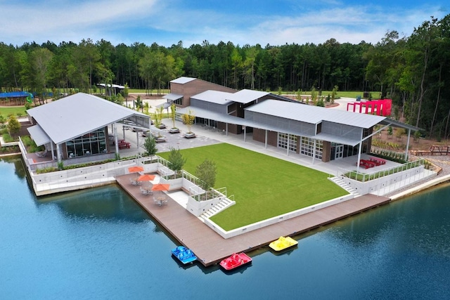 rear view of house with a water view, a view of trees, and a yard