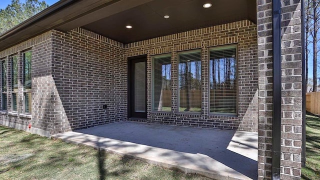 doorway to property featuring a patio area and brick siding