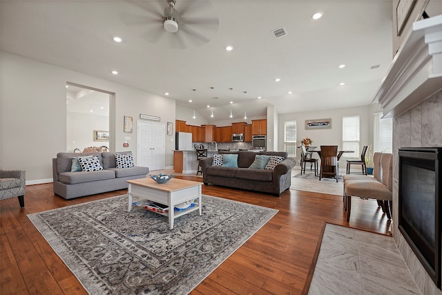 living room with wood-type flooring, a tile fireplace, and ceiling fan