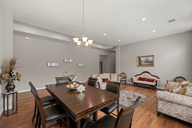 dining space featuring dark wood-type flooring and an inviting chandelier