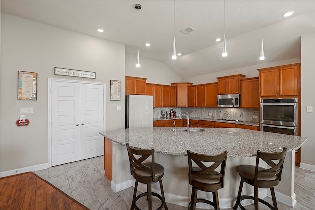 kitchen featuring light hardwood / wood-style flooring, tasteful backsplash, an island with sink, stainless steel appliances, and sink