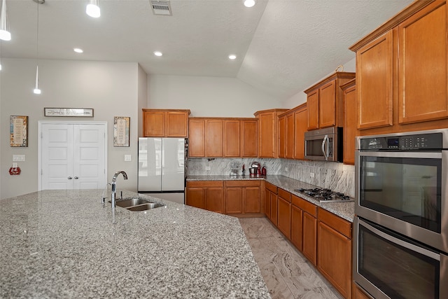 kitchen featuring high vaulted ceiling, appliances with stainless steel finishes, light stone counters, and sink