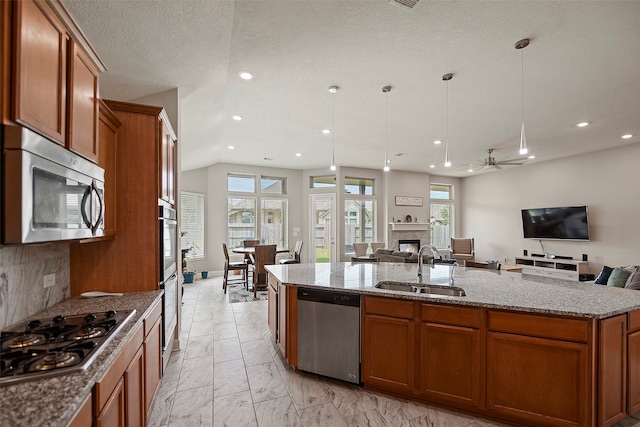 kitchen featuring stone countertops, a kitchen island with sink, stainless steel appliances, sink, and ceiling fan