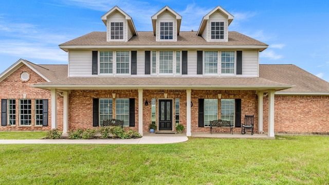 view of front of home with brick siding, a front yard, and a shingled roof