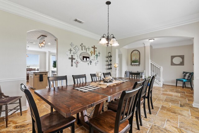 dining area with arched walkways, a chandelier, stone tile floors, stairs, and crown molding