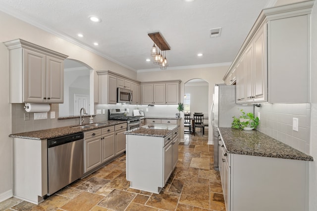 kitchen with stone tile flooring, appliances with stainless steel finishes, arched walkways, and a sink