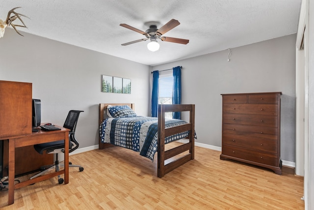 bedroom with a ceiling fan, baseboards, a textured ceiling, and light wood finished floors