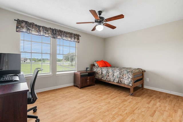 bedroom with light wood finished floors, baseboards, and a ceiling fan