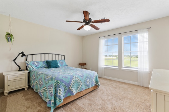 bedroom with baseboards, a textured ceiling, a ceiling fan, and light colored carpet