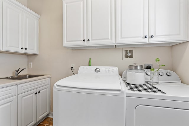 laundry room with washing machine and dryer, cabinet space, and a sink