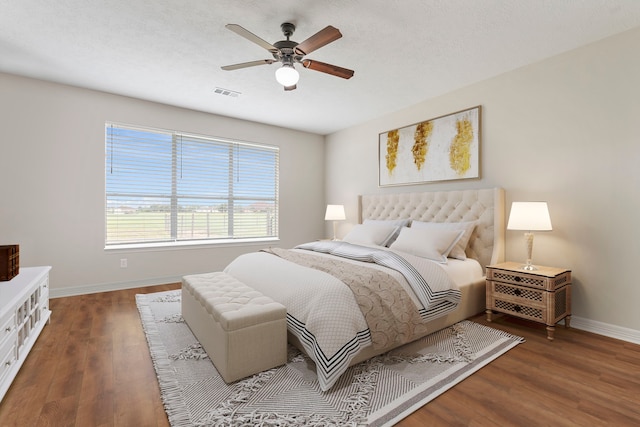 bedroom featuring a ceiling fan, visible vents, baseboards, and wood finished floors