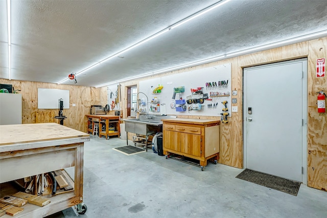 below grade area with wood walls, a textured ceiling, and a workshop area