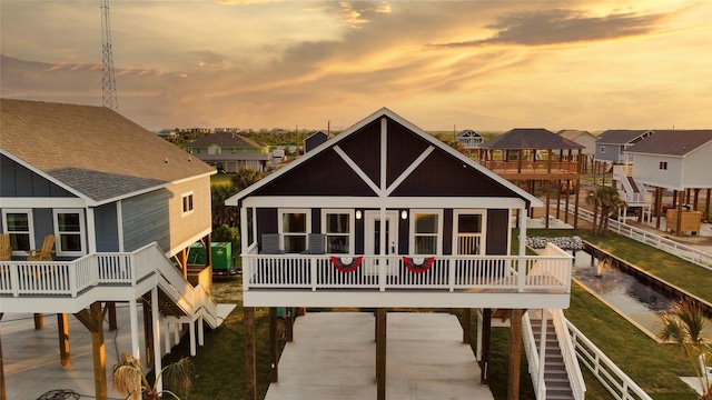 rear view of property with stairs, a shingled roof, board and batten siding, and a residential view