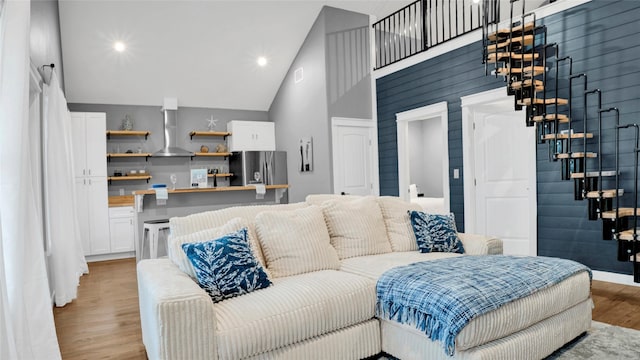 living area with high vaulted ceiling, recessed lighting, and light wood-style floors