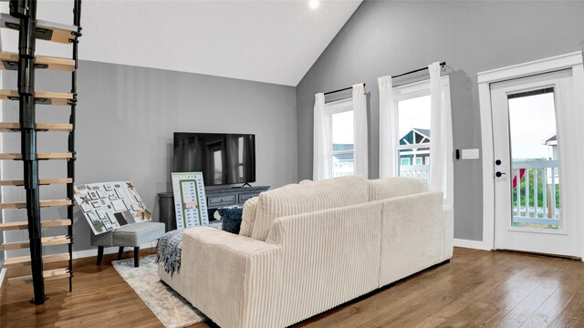 living room featuring high vaulted ceiling, baseboards, and wood finished floors