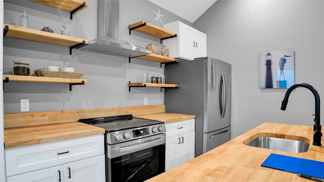 kitchen with wall chimney exhaust hood, a sink, stainless steel appliances, open shelves, and wooden counters