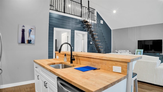 kitchen featuring butcher block countertops, a sink, stainless steel dishwasher, and wood finished floors