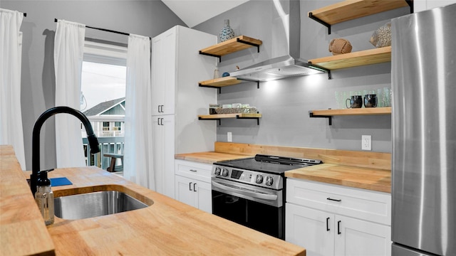 kitchen featuring appliances with stainless steel finishes, wooden counters, wall chimney exhaust hood, and open shelves