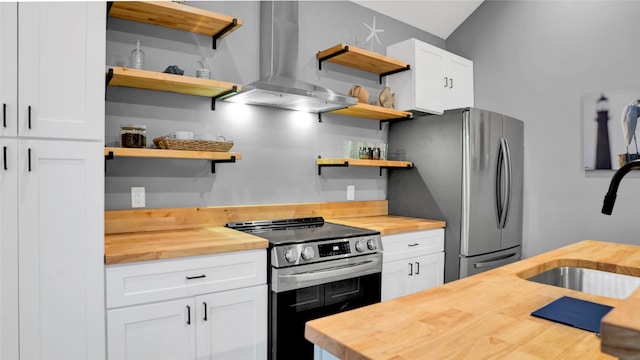 kitchen featuring appliances with stainless steel finishes, wall chimney exhaust hood, white cabinetry, and wood counters